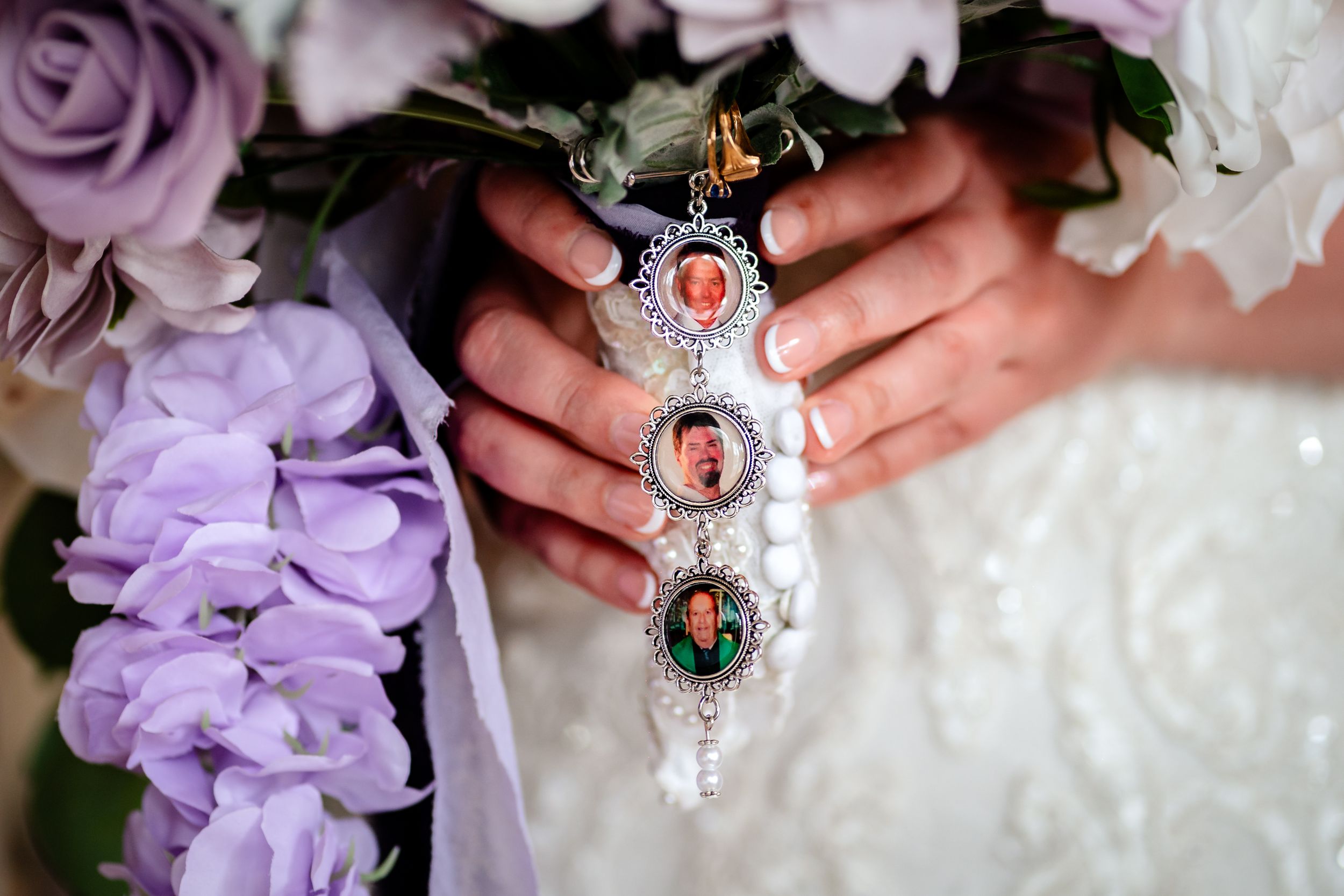 Wedding bouquet detail showing vintage-style jewelry with purple and white flowers.