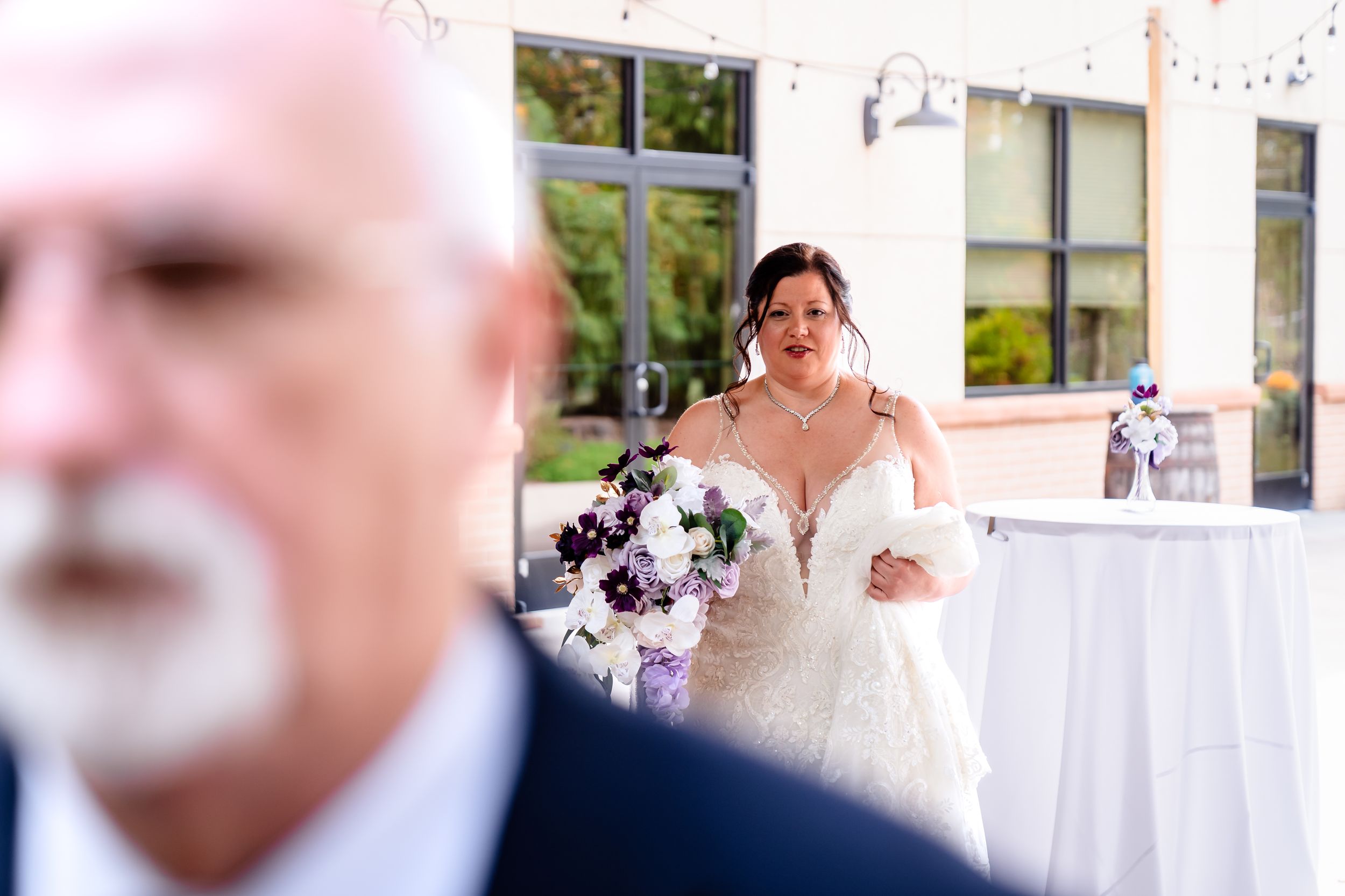 Candid wedding moment captured through guests during outdoor reception.