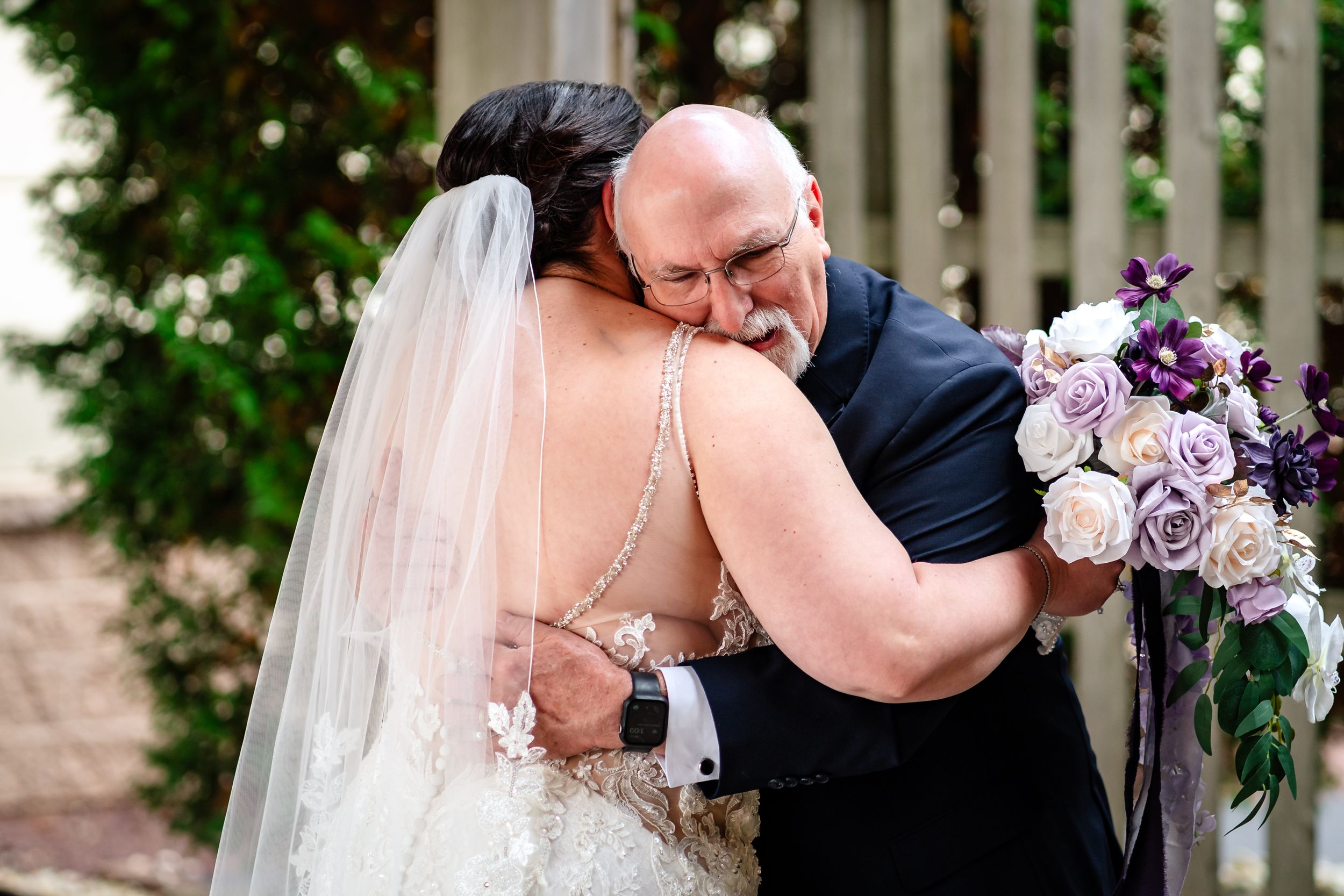 A romantic wedding moment captured in a garden gazebo with white lattice and greenery.