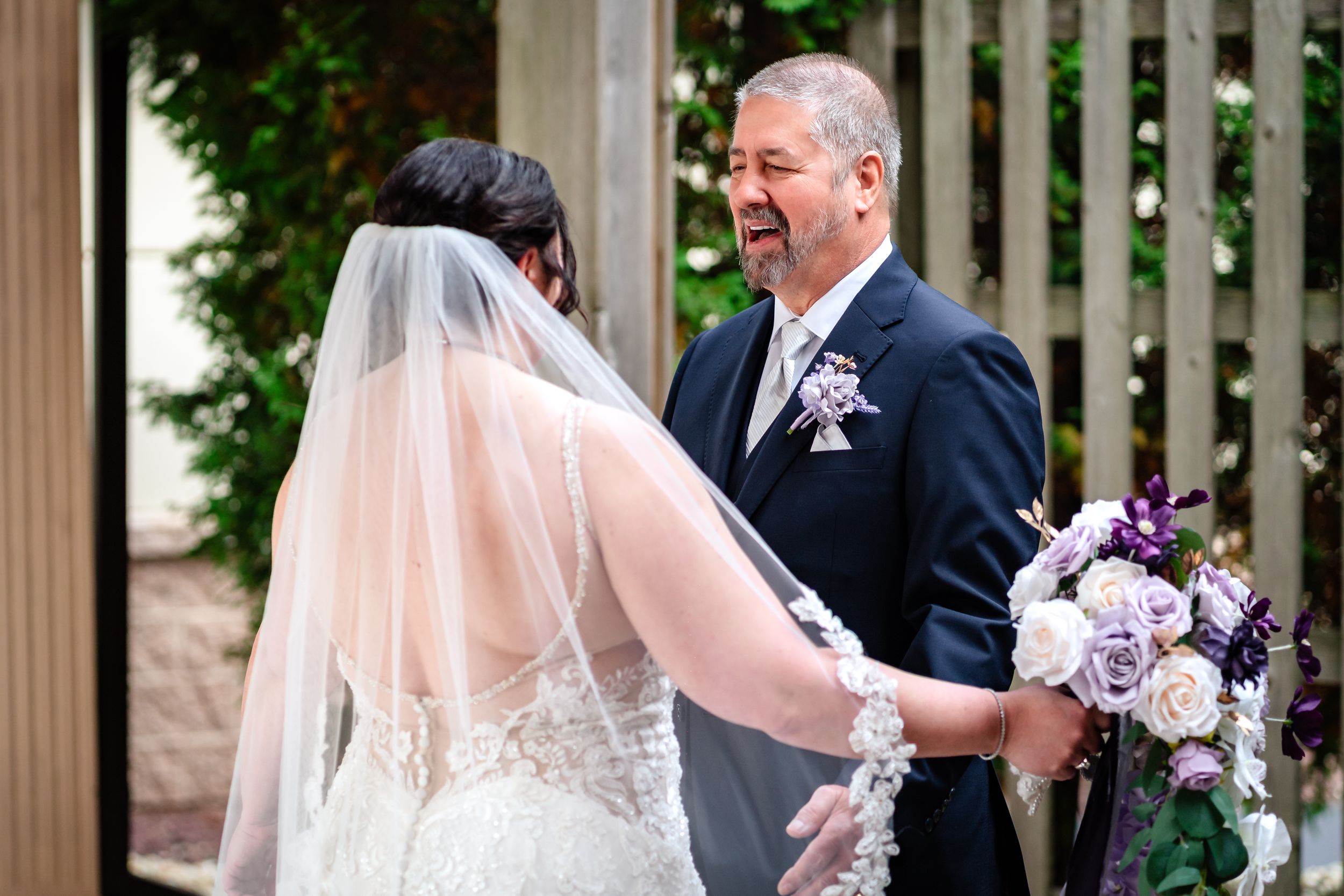 Tender wedding kiss scene under an elegant white gazebo surrounded by lush greenery.