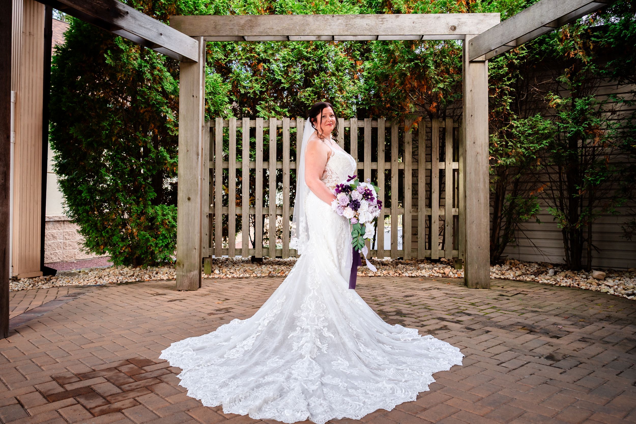 Beautiful white lace wedding dress with long train photographed in garden setting.