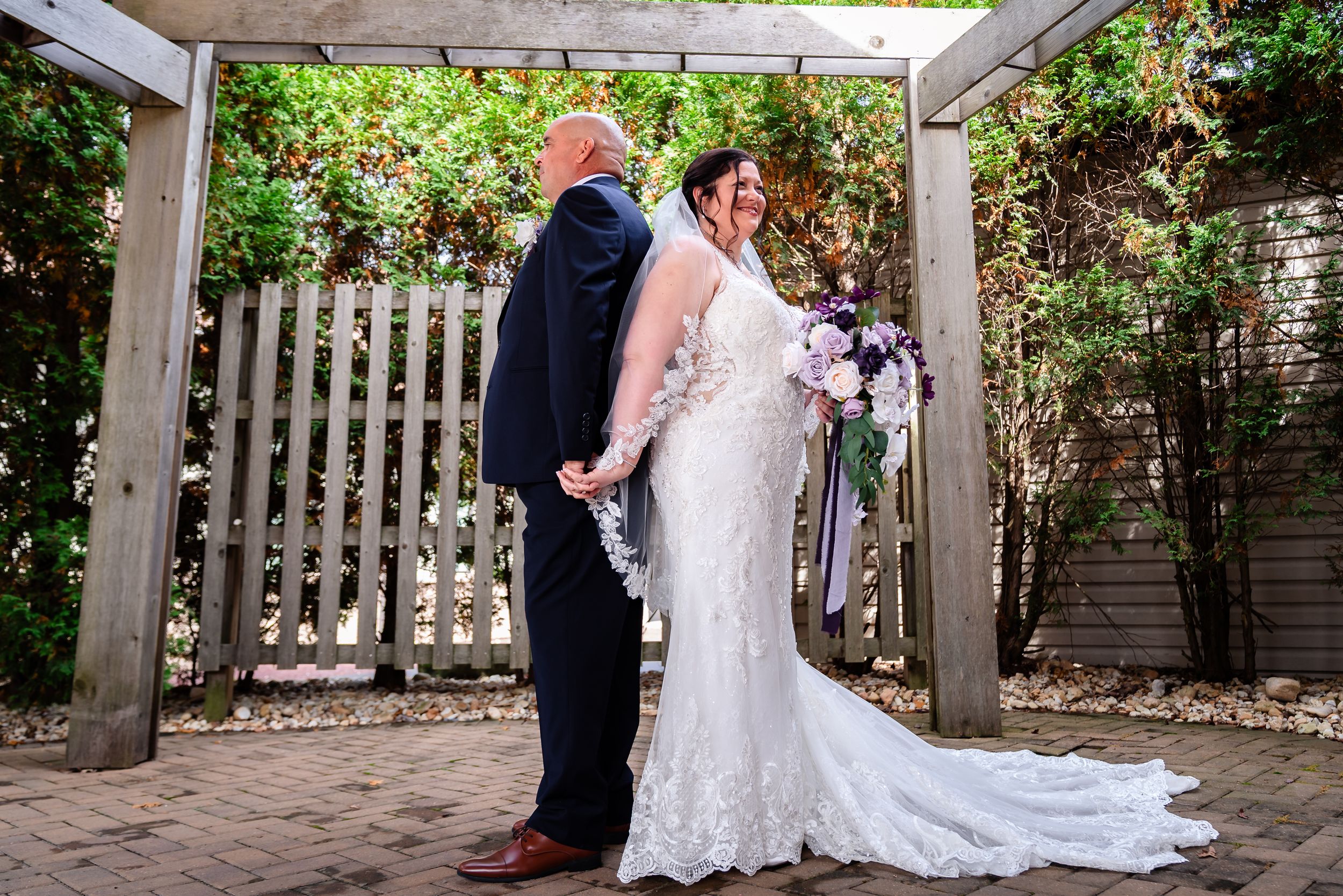 Wedding couple sharing intimate moments in outdoor garden setting with white lattice backdrop.