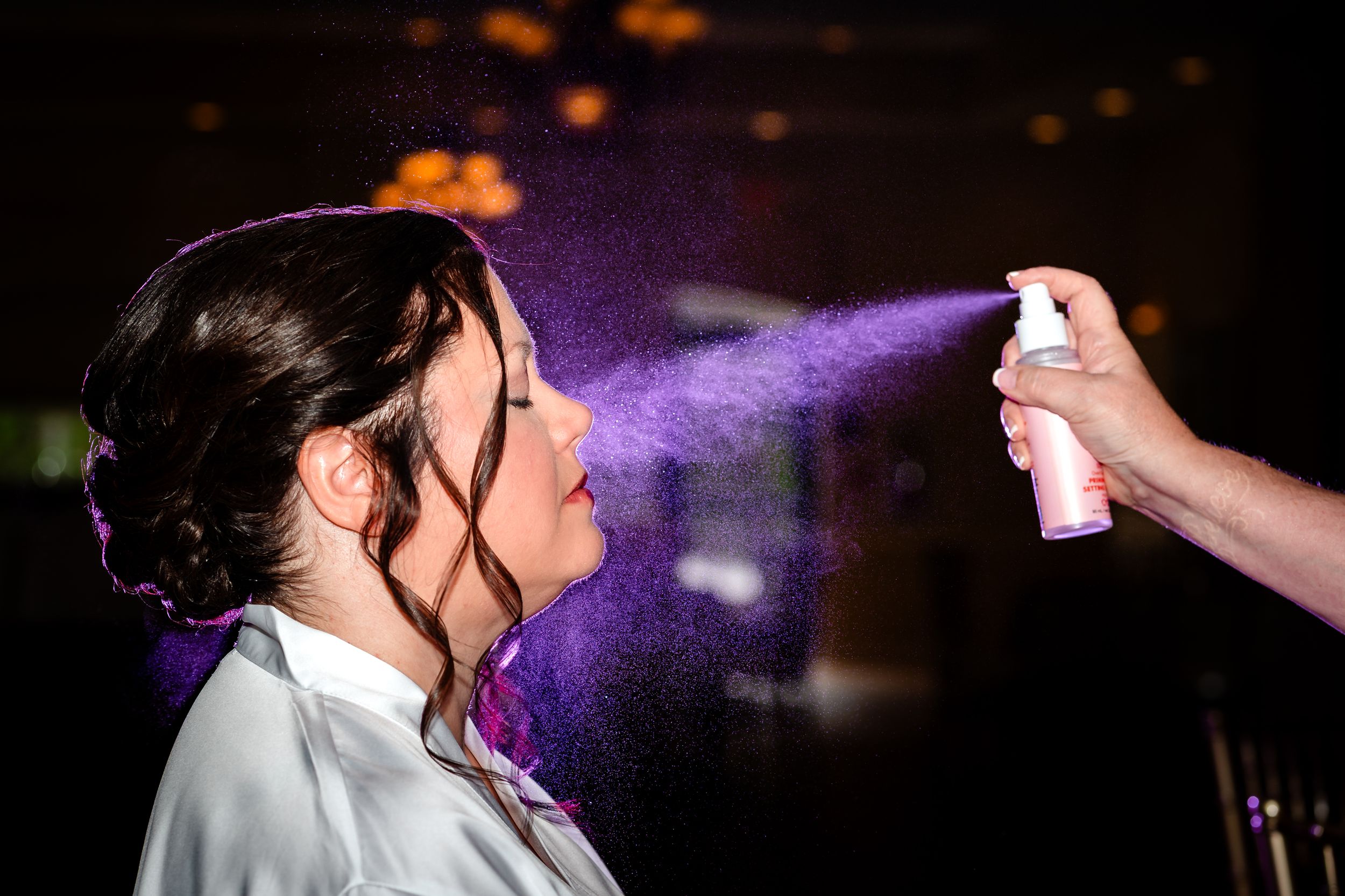 Purple lighting effects and hairspray being used during wedding preparations.