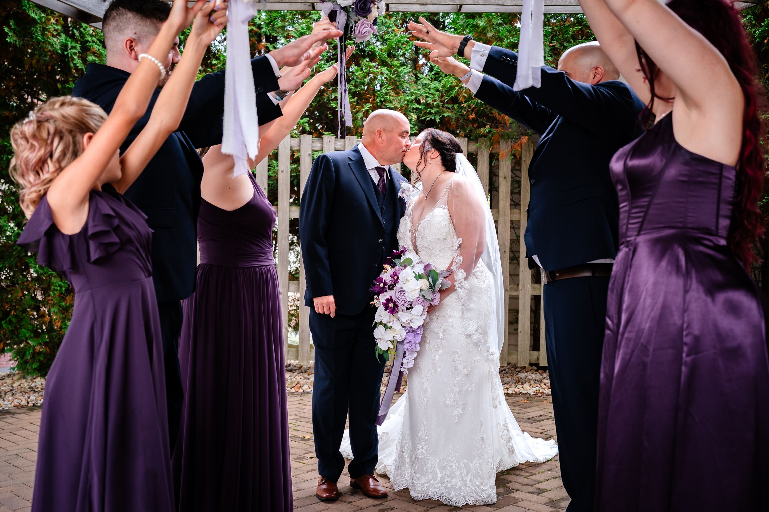 Wedding party members celebrate outdoors with joyful expressions and formal attire.