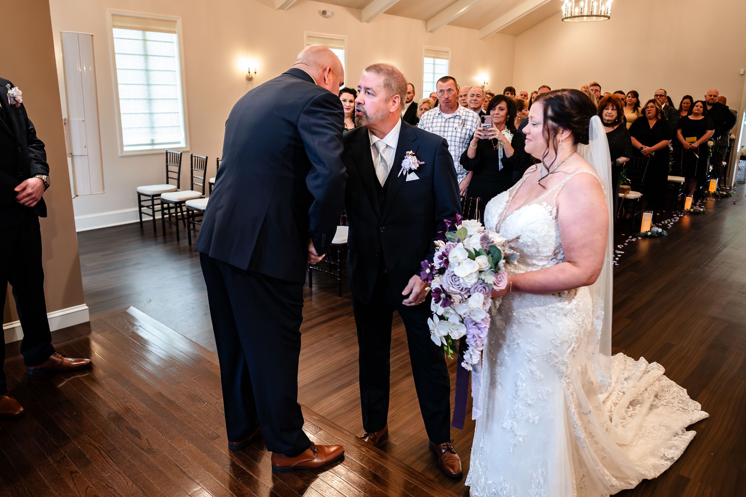 Indoor wedding ceremony with guests watching as couple exchanges vows at the altar.