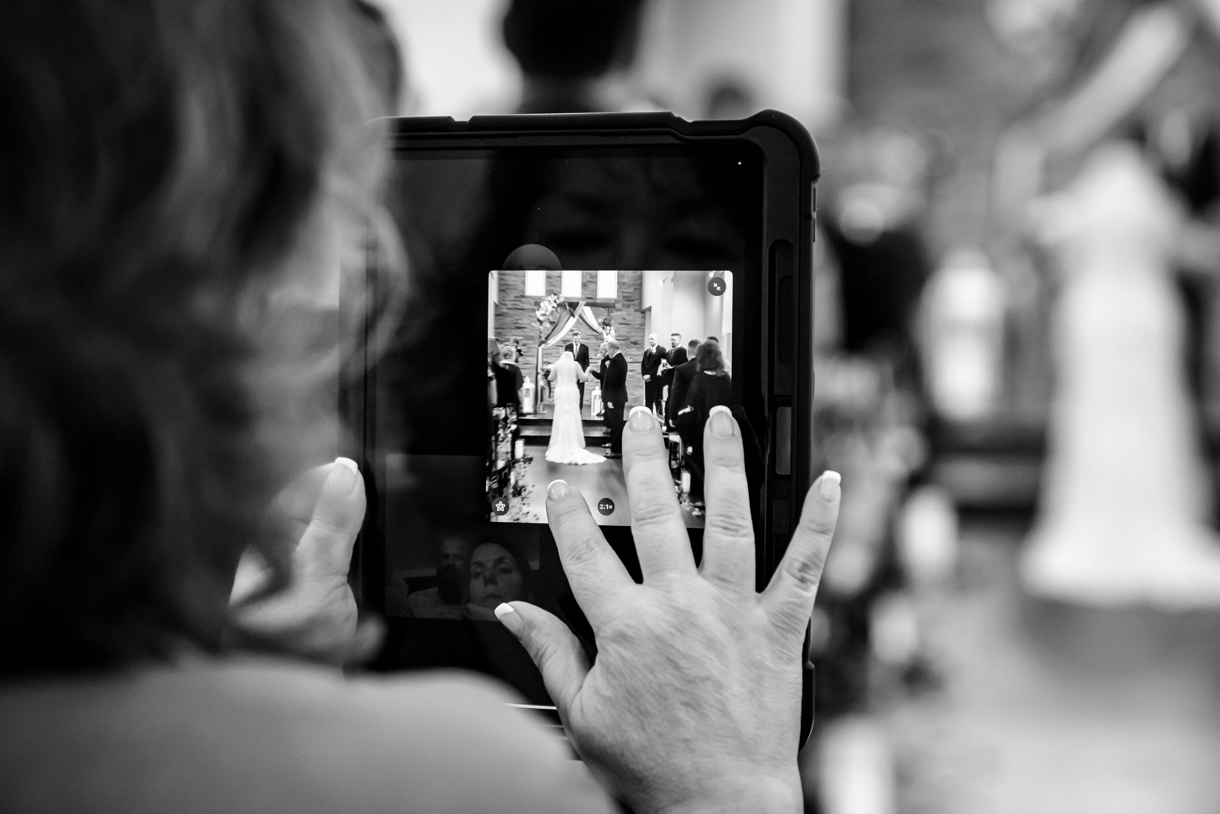 Black and white photo sequence of hands holding phones to capture wedding moments.