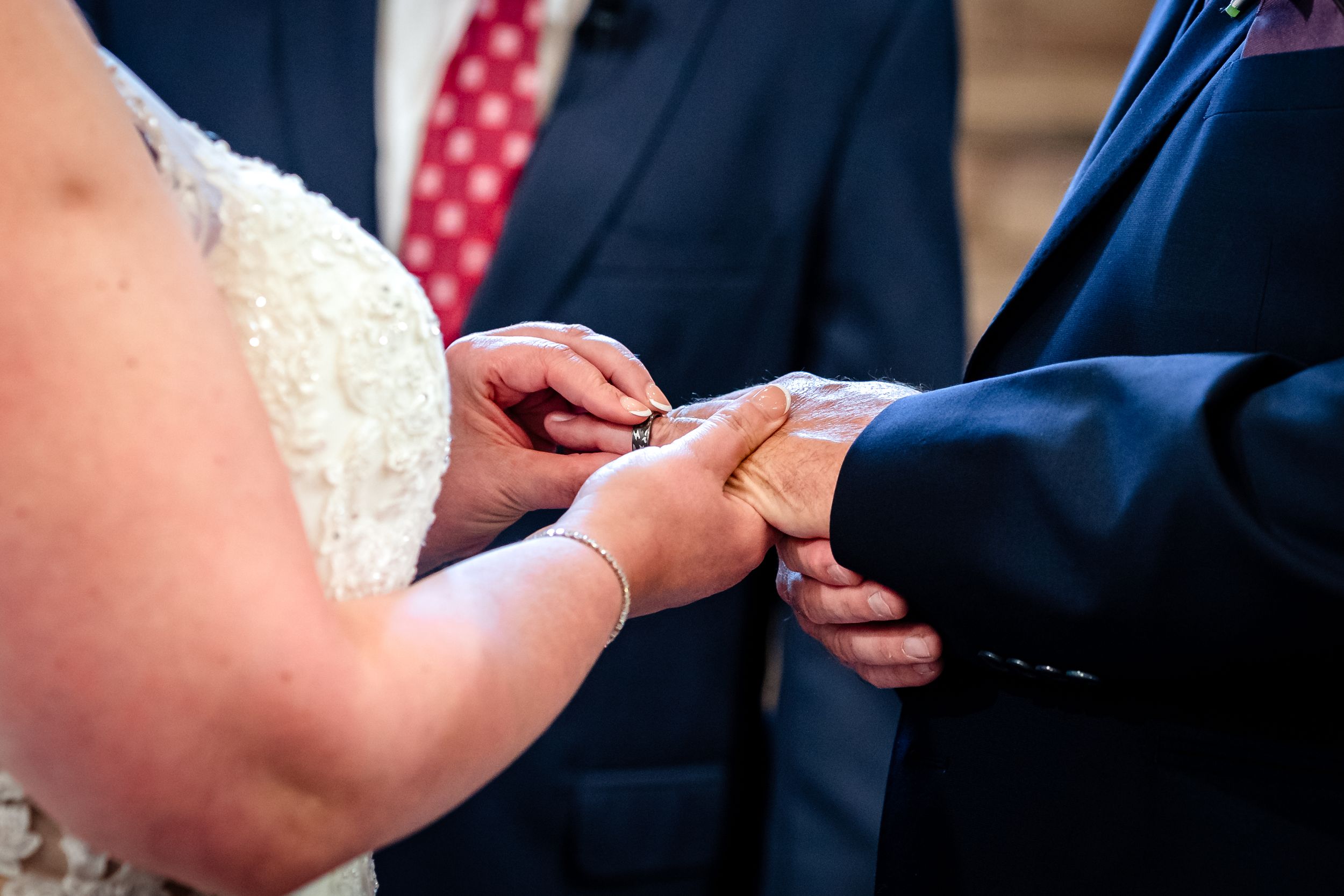 Close-up of hands during wedding ring exchange ceremony.