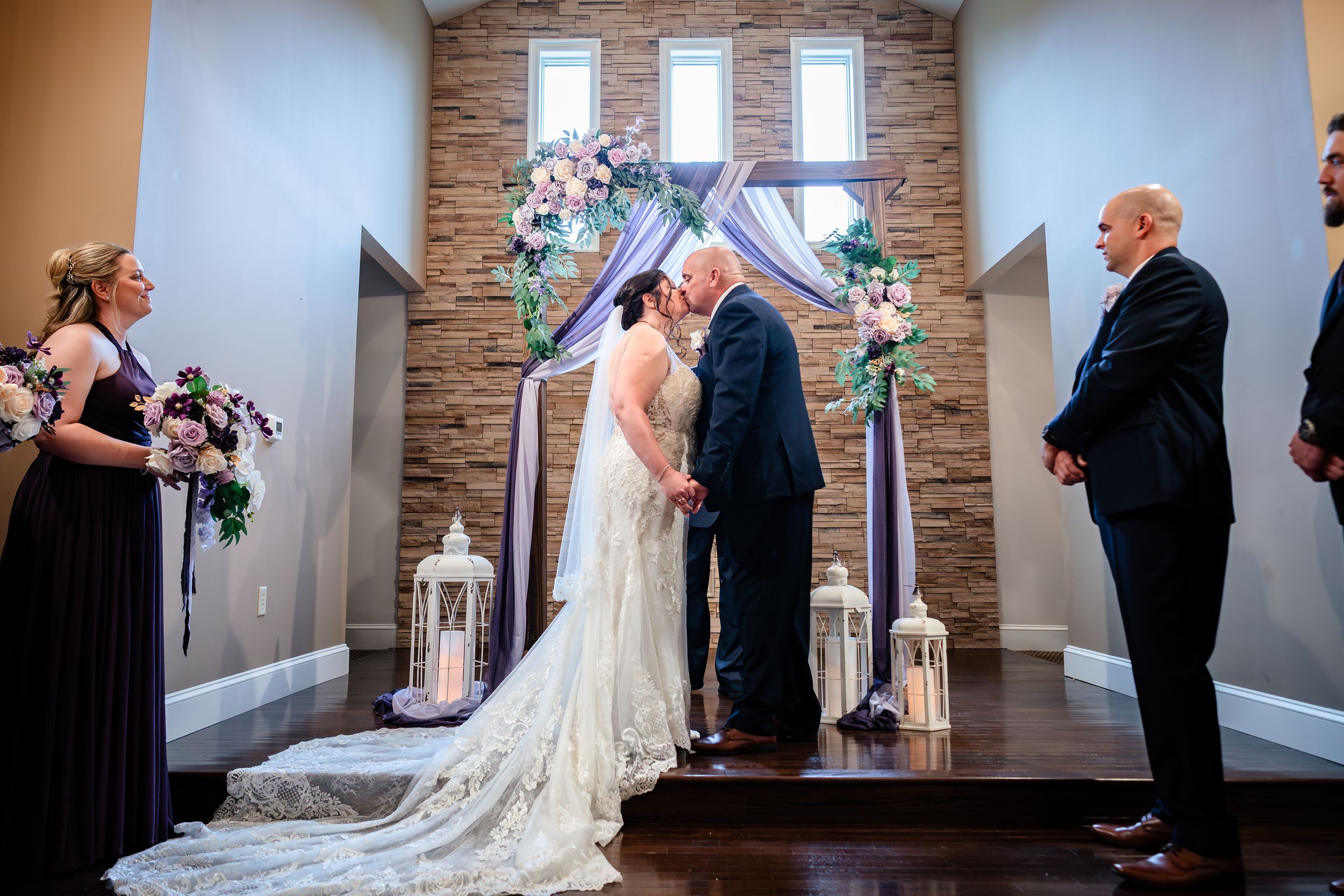 A wedding ceremony takes place in an elegant chapel with stone walls and floral decorations.
