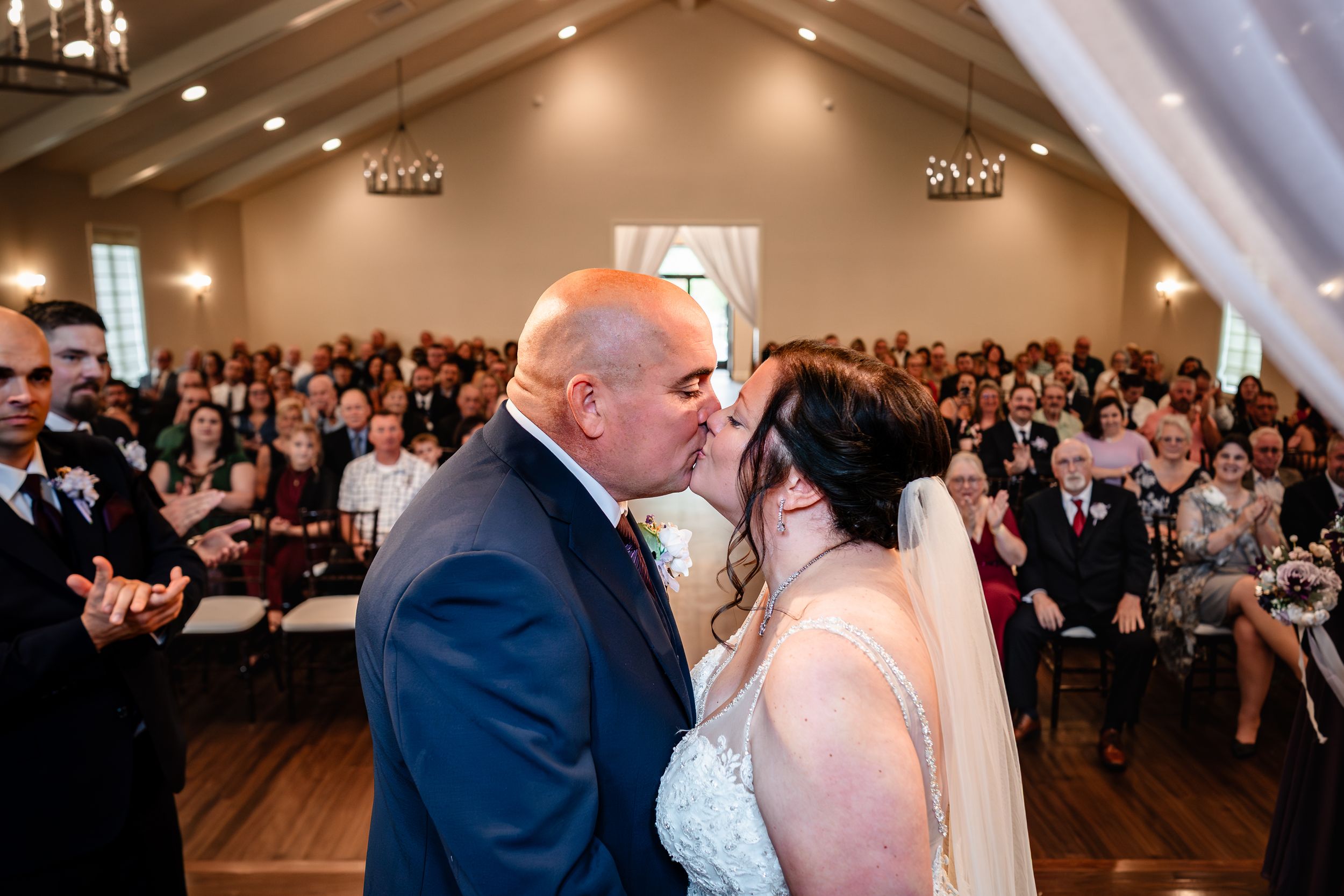 Wedding ceremony in spacious venue with wooden floors and vaulted ceilings.