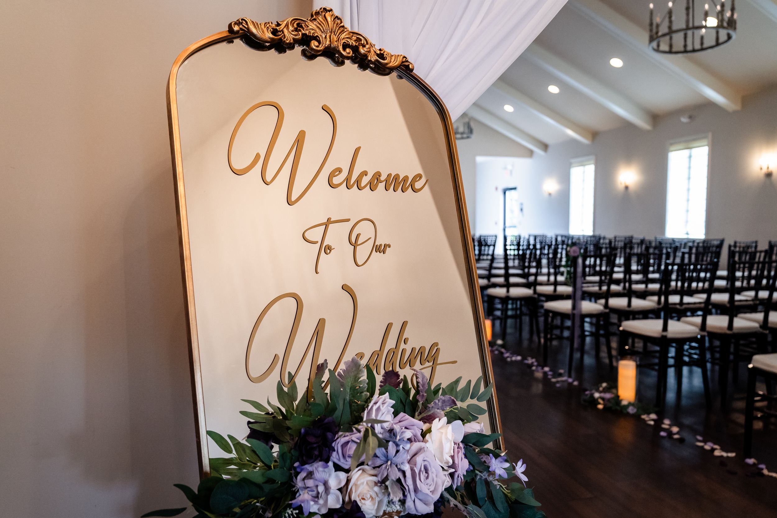 Wedding venue interior decorated with elegant welcome sign and rows of chairs.
