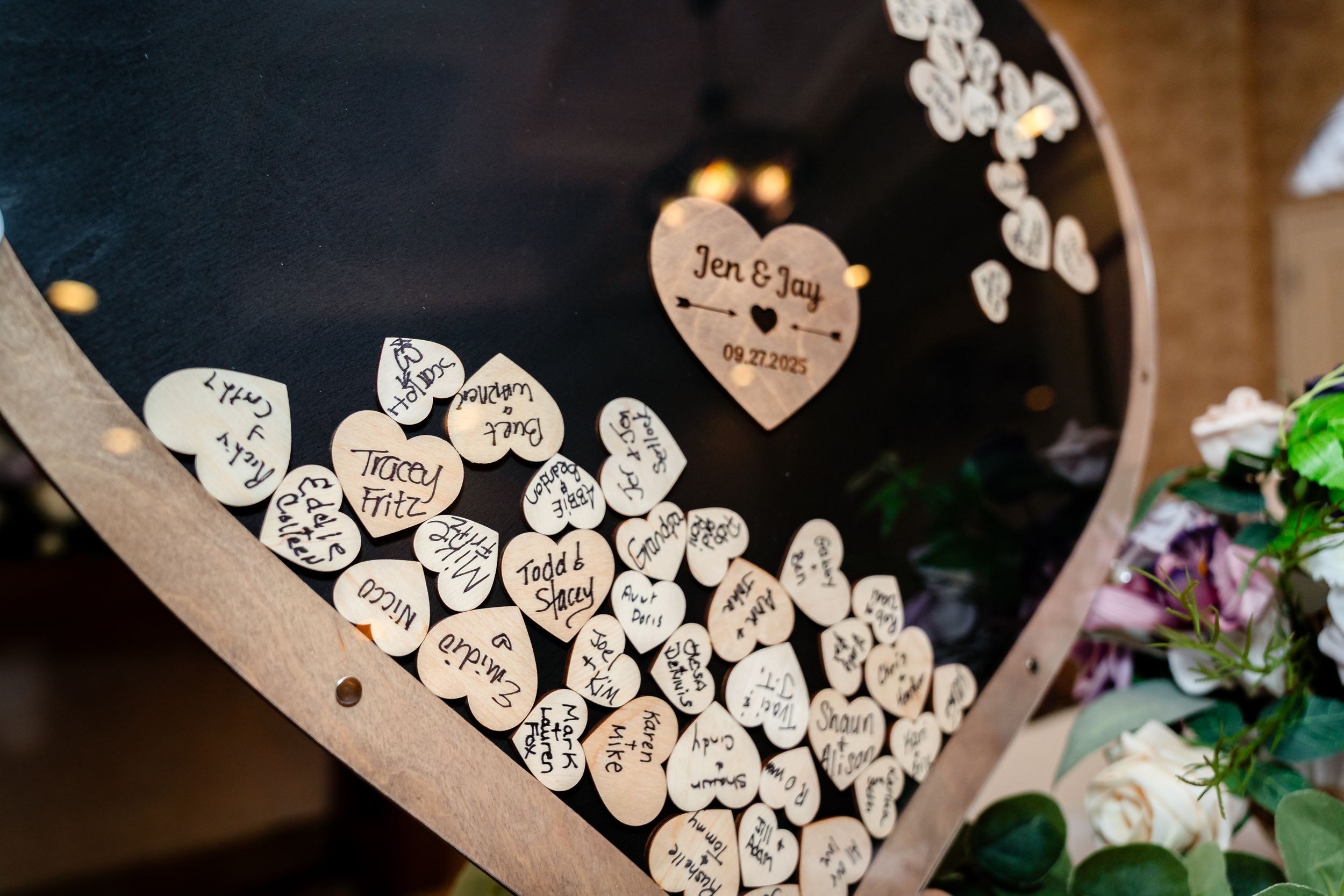 Wooden hearts with signatures displayed as a creative wedding guest book alternative.