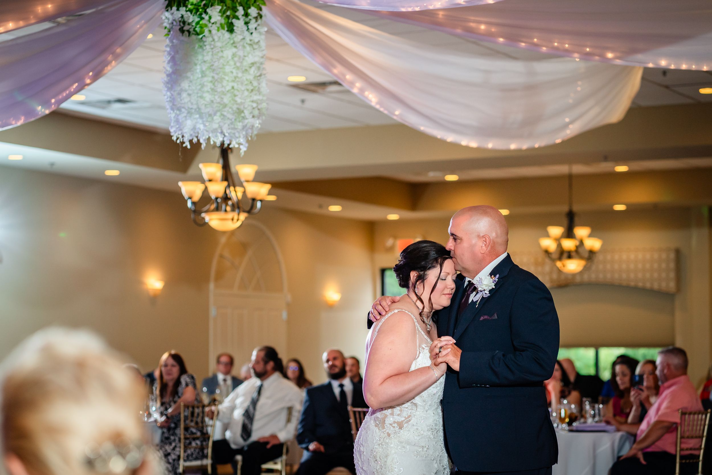 Wedding reception venue decorated with elegant chandeliers and white drapery for evening celebration.