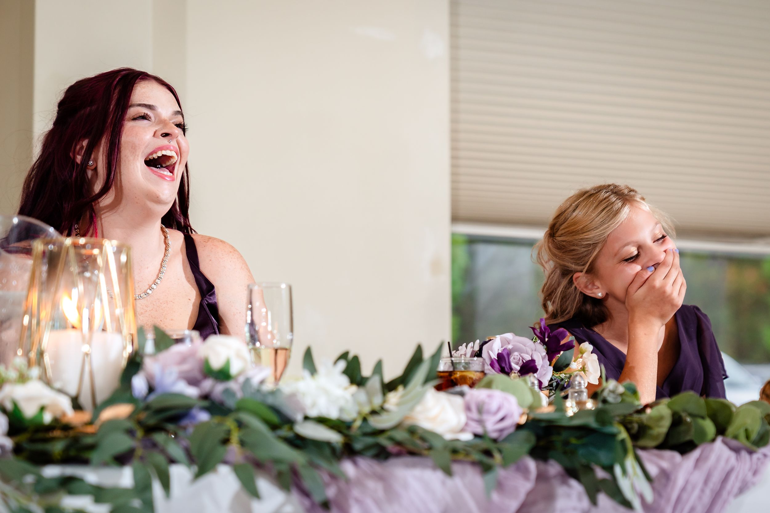 Purple floral arrangements and greenery decorate an elegant wedding reception table.