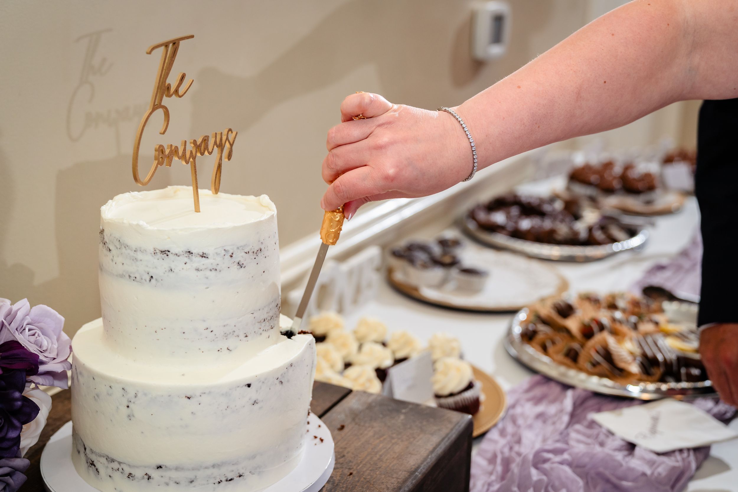 White wedding cake with elegant gold details displayed at reception.