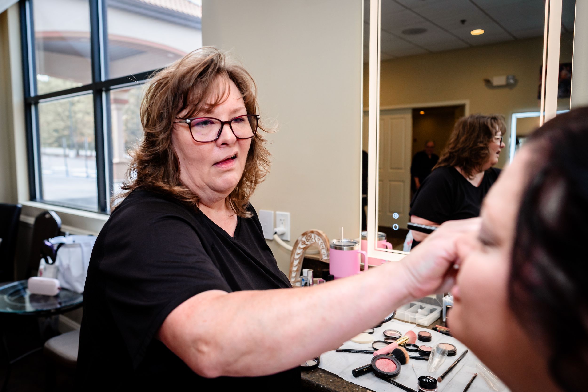 Wedding day makeup application and preparation in a bright room with windows.
