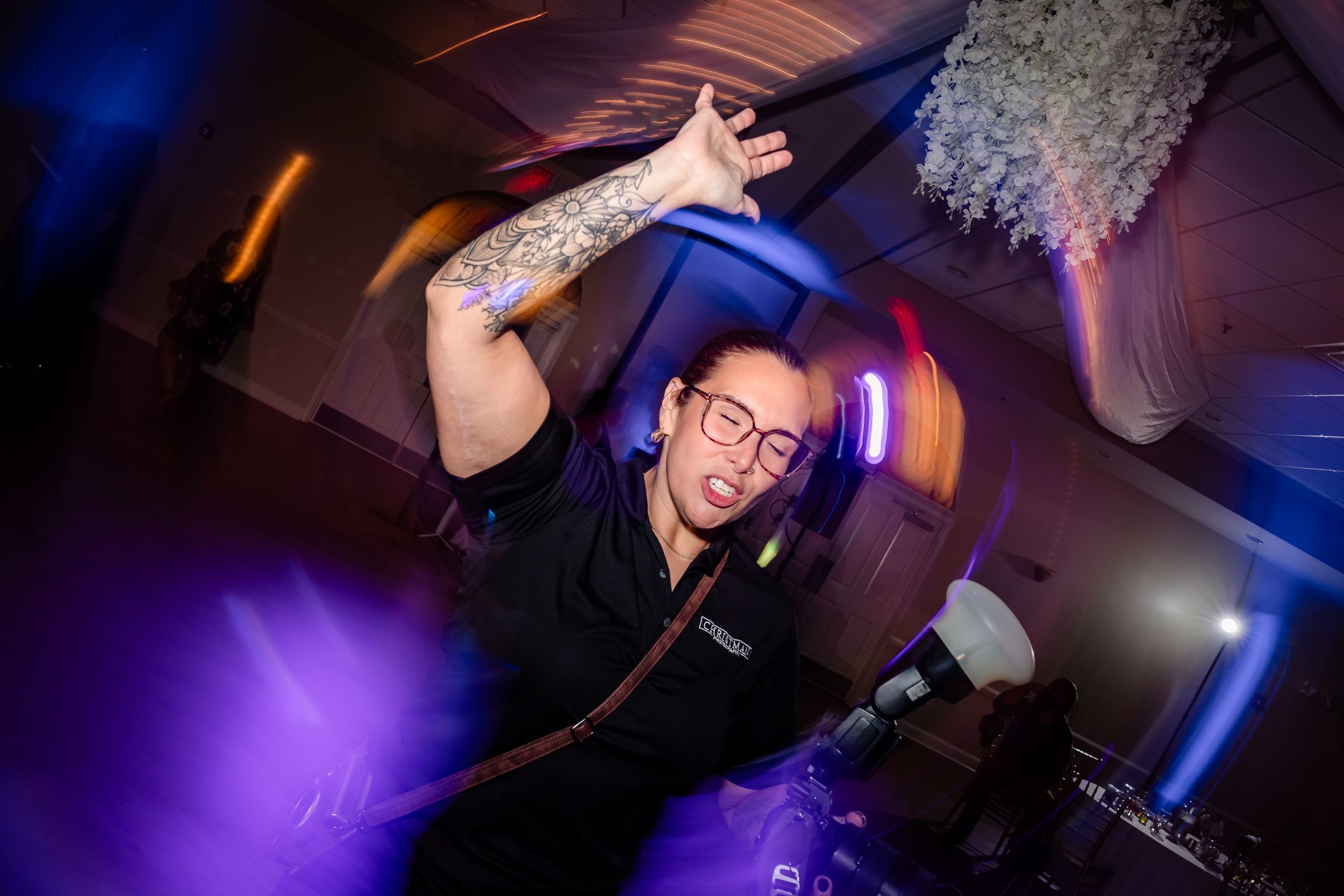 Energetic dance floor moments captured with colorful lighting at wedding reception.