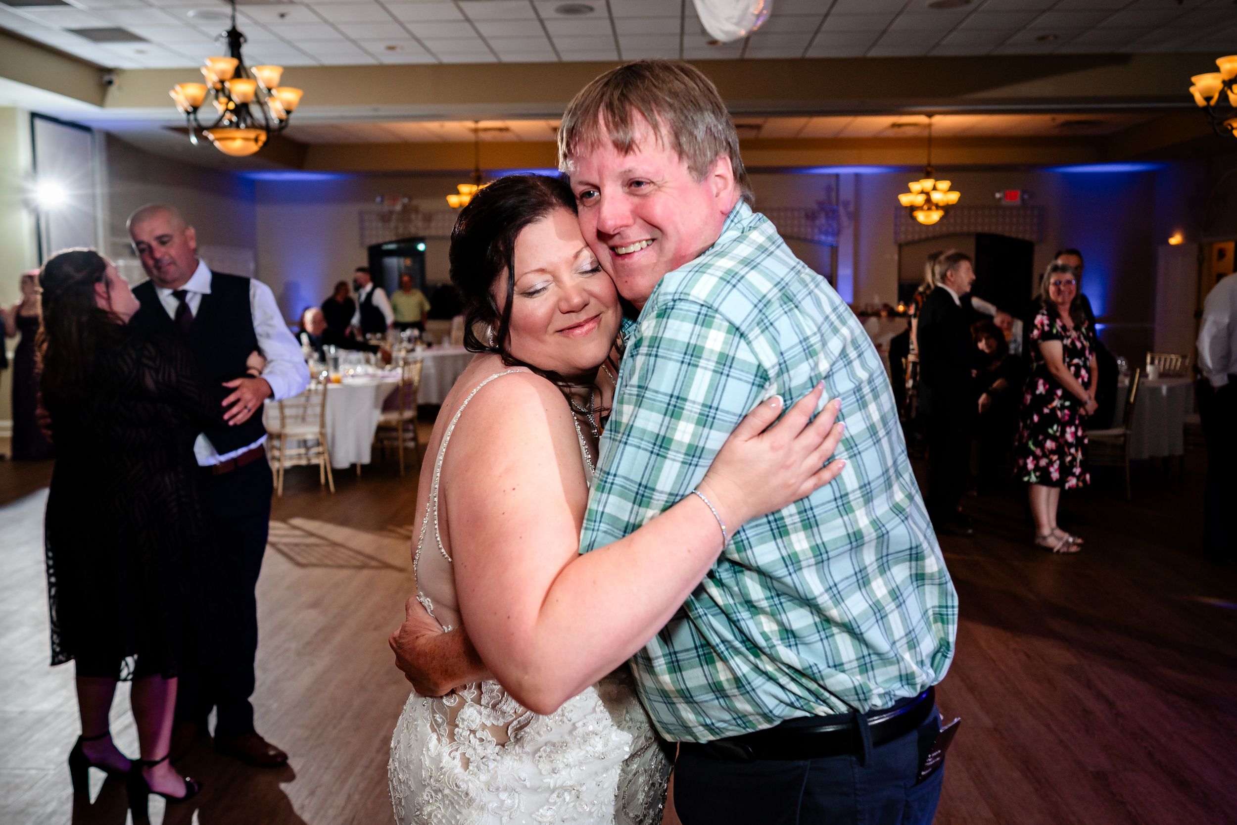 Couples dancing and celebrating on wooden dance floor at wedding reception.