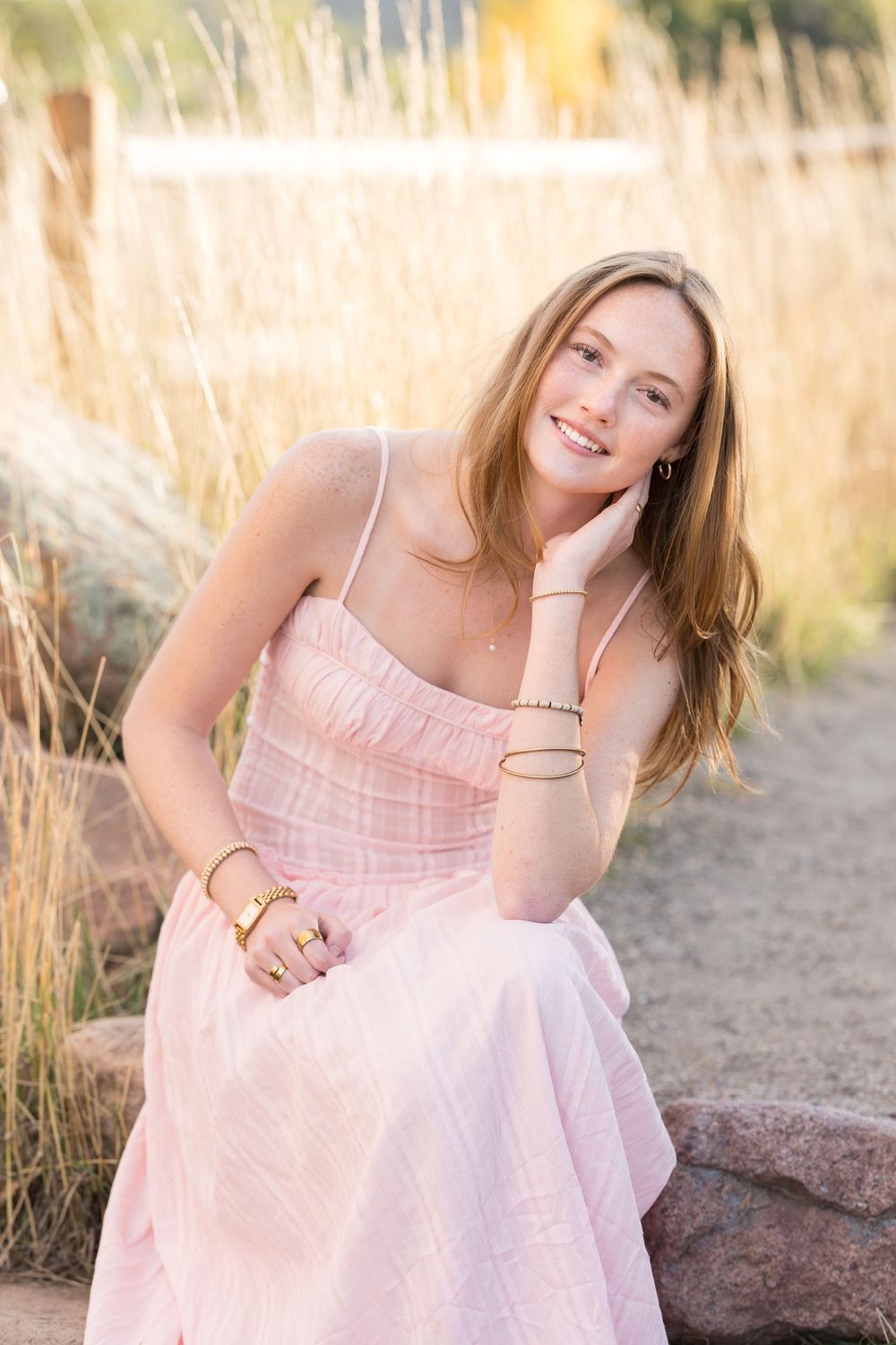Soft pink sundress captured in a golden field at sunset with mountains in the background.