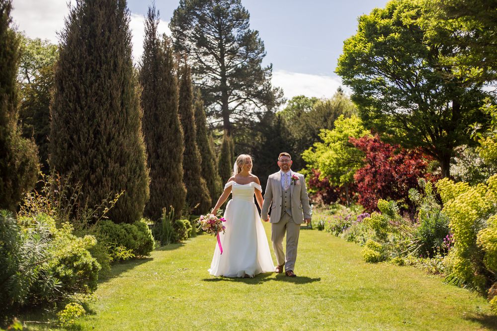 Scenic garden wedding photography with tree-lined path and vibrant greenery.