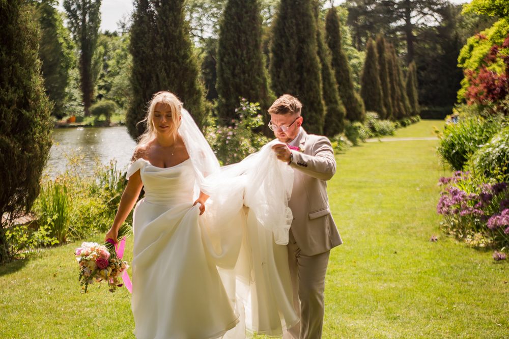 A couple poses in a scenic garden setting with vibrant flowers and trees.