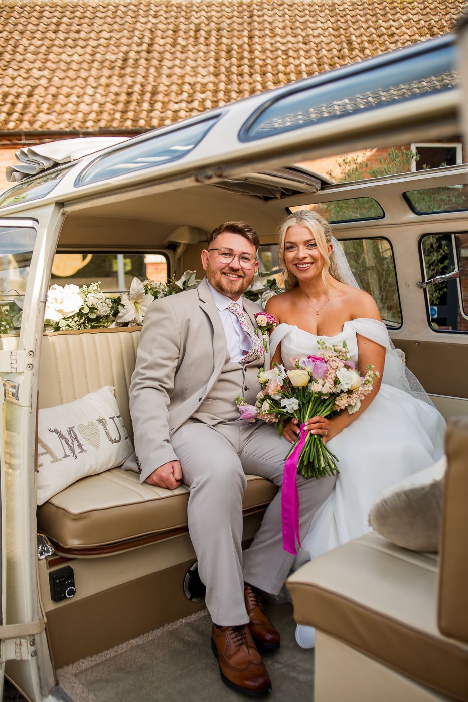 Wedding couple seated inside a vintage Volkswagen van with cream interior.