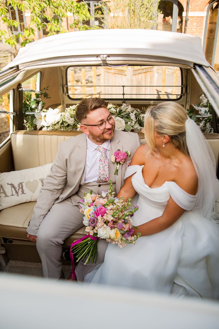 Couple sharing intimate moments inside a classic VW campervan with floral bouquet.