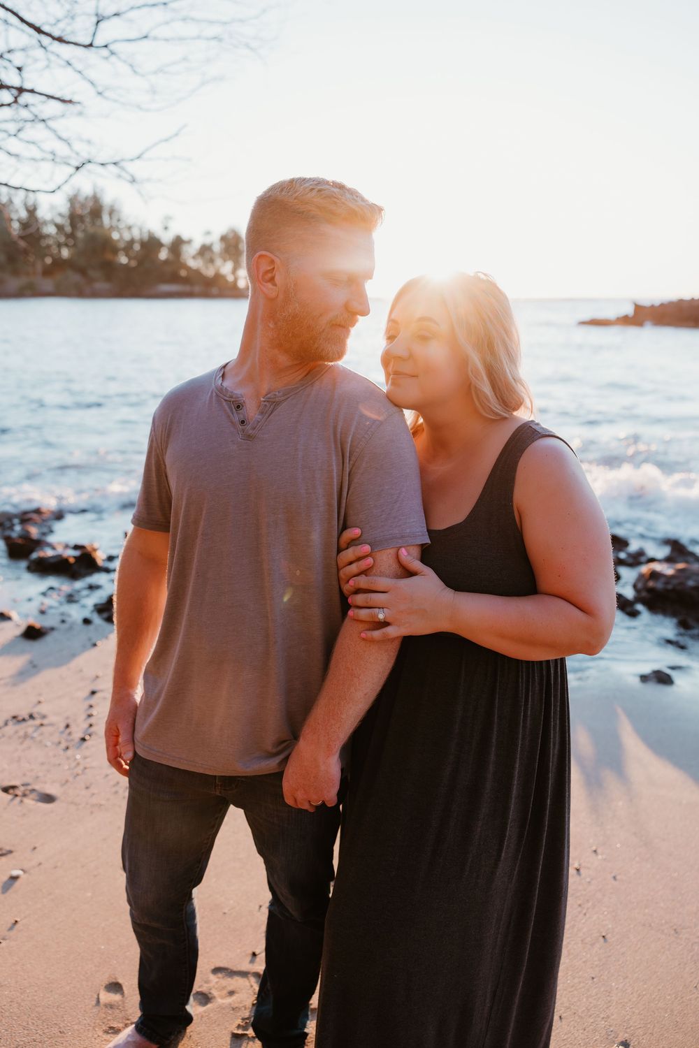 A couple walks together on a sunny beach during golden hour, creating a romantic silhouette against the ocean.