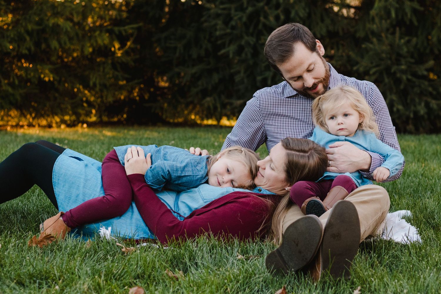 Happy family relaxing together on green grass in a park during autumn.