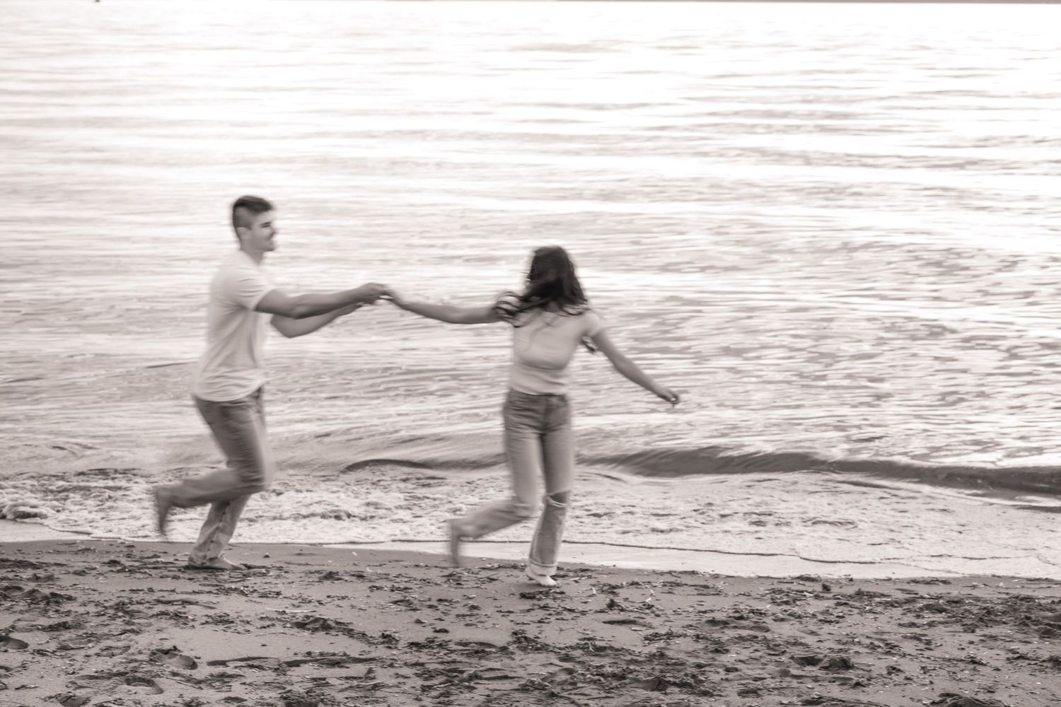 A romantic sequence of black and white photos showing a couple dancing and playing together on a beach at sunset.