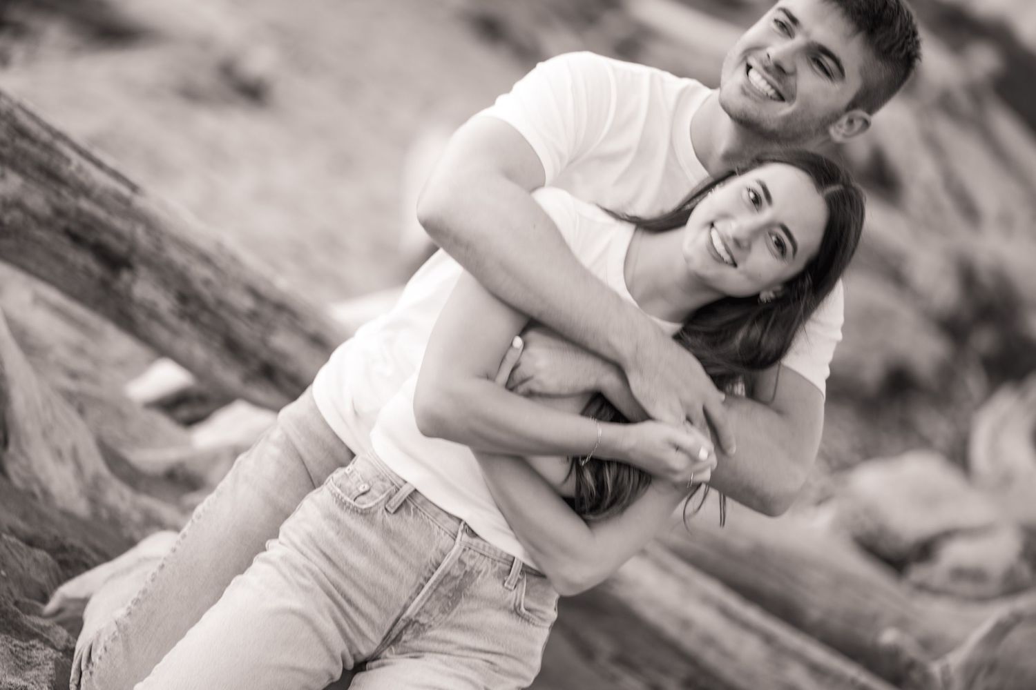 A series of black and white romantic engagement photos showing a couple embracing on a rocky outdoor setting.