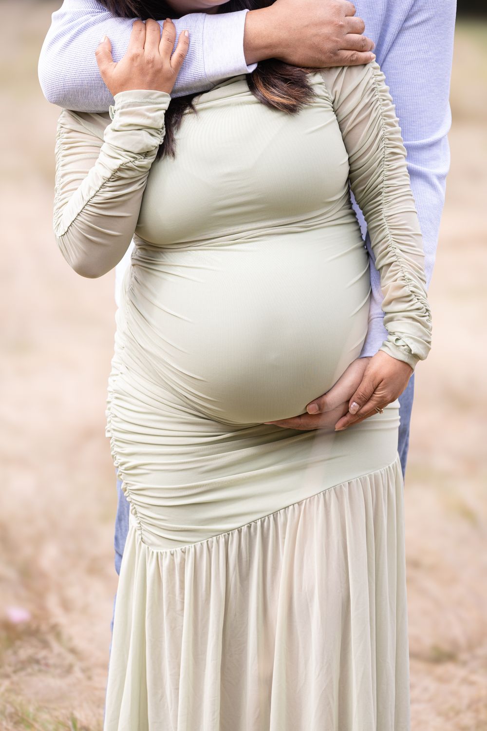 Close-up progression shots of a pregnant belly in a cream-colored dress showing growth over time.