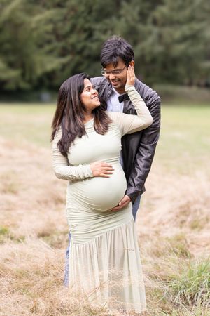 A couple embraces lovingly in a field of golden grass during an outdoor photo session.
