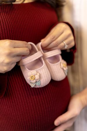 A sequence of close-up shots showing small pink baby shoes with delicate flower embellishments.