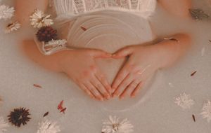 Delicate white snowflake decorations scattered on a pink surface with hands visible in the background.