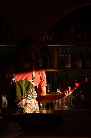Dimly lit bar interior with bottles silhouetted against warm ambient lighting.