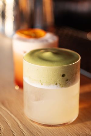 Layered matcha dessert with white cream base served in an elegant glass.