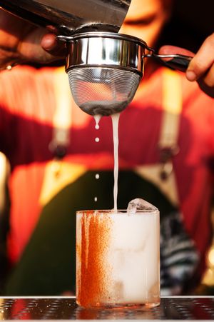 Liquid being poured into a frosted cocktail glass over ice.