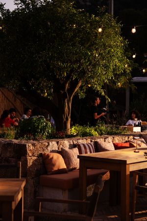Outdoor seating area with wooden benches and string lights creating a cozy evening atmosphere.