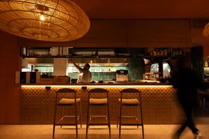 Modern restaurant interior with bar seating and ambient lighting.
