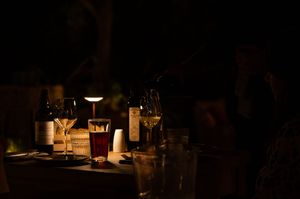 Candlelit table settings create an intimate dining atmosphere in a dimly lit restaurant.