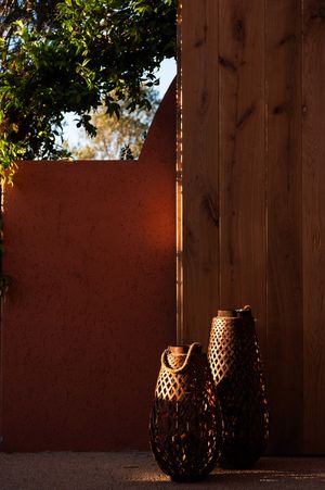 Decorative lanterns casting shadows against wooden wall at dusk.