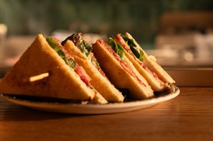 Club sandwiches arranged diagonally on a wooden surface in dim lighting.