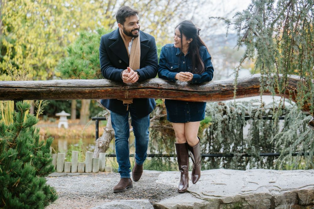 Couple sitting together on rustic wooden bench in autumn garden setting.
