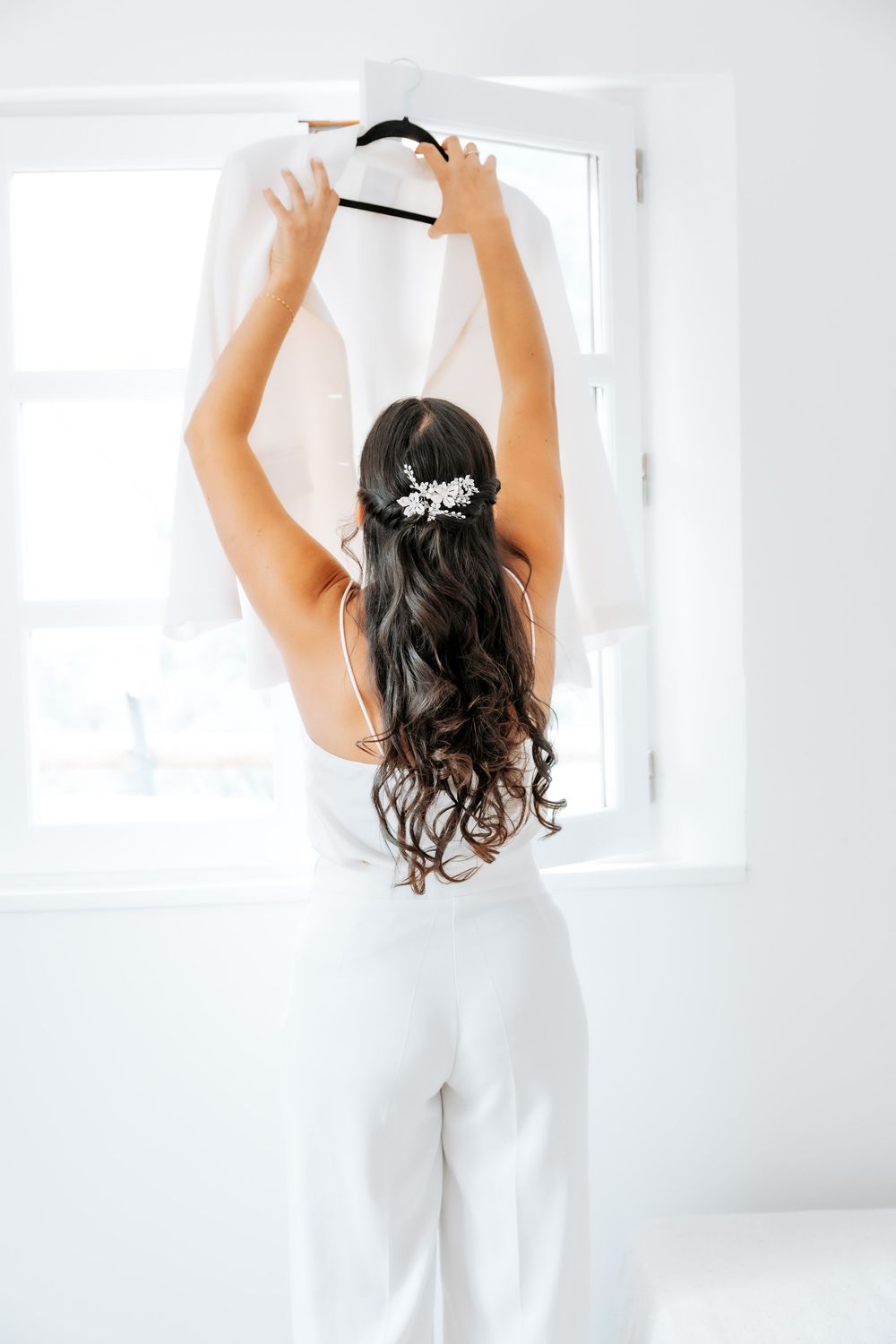 A person in white raises their arms while standing in a bright, airy room.