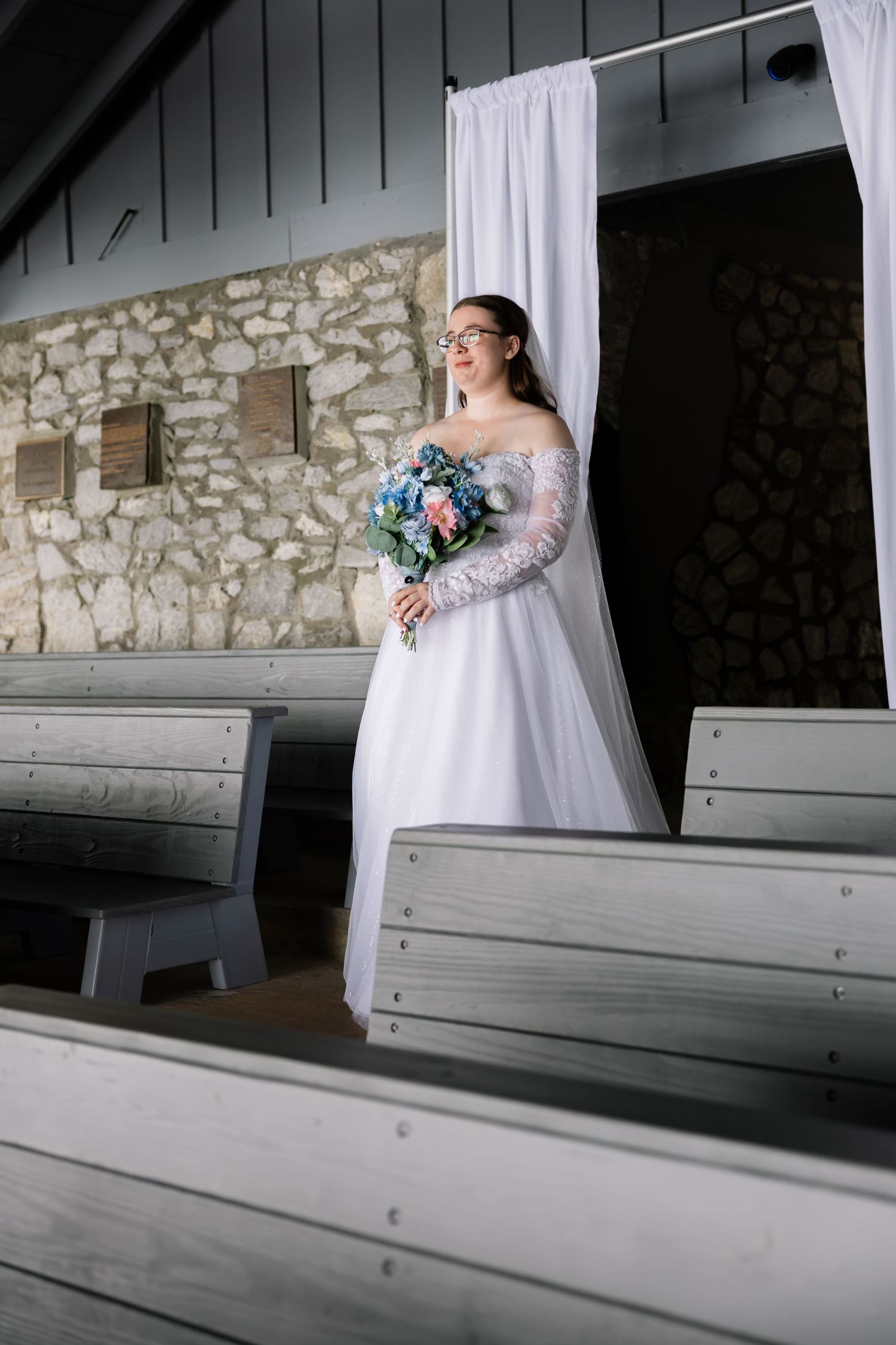 A row of white wedding dresses on display with guests seated in church pews during an elegant ceremony.