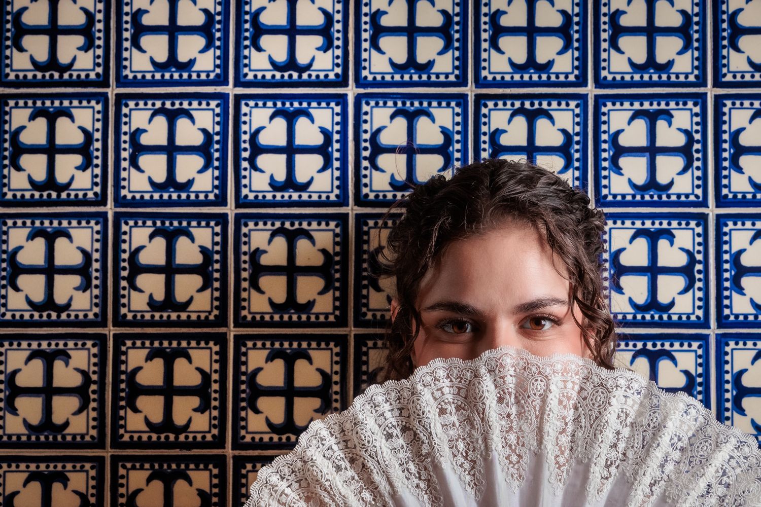 Artistic portrait incorporating decorative blue and white tile patterns as a creative backdrop.