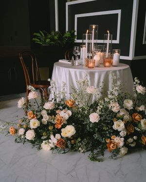 Elegant wedding sweetheart table at the Fitzgerald venue in Milwaukee; adorned with white linen, candles, and lush orange and white florals.
