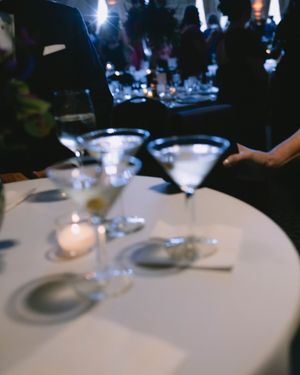 Elegant martini glasses and a candle on a white tablecloth at a dimly lit wedding reception.