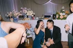 Wedding guests in blue dress and suit laughing together near floral centerpiece at Dallas reception.