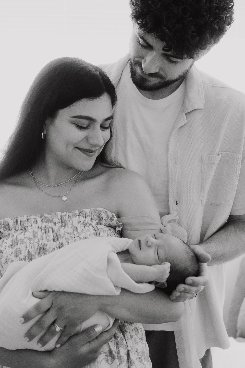 Black and white photo series showing tender moments between parents and their newborn baby in intimate close-ups.